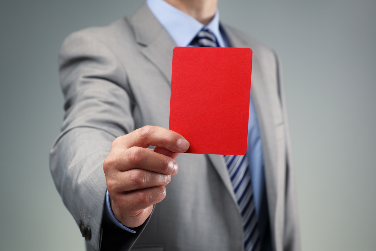 a man in a grey suit holds up a red penalty card. DraftKings Fined By Ontario Regulator for Alleged Violations. DraftKings Ontario allegedly ran afoul of the same rule that tripped up BetMGM Ontario and PointsBet Ontario in early May.